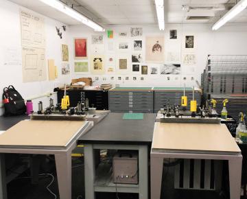 Drafting tables in a room with prints on the wall behind