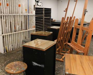 Easels and work tables next to a canvas locker