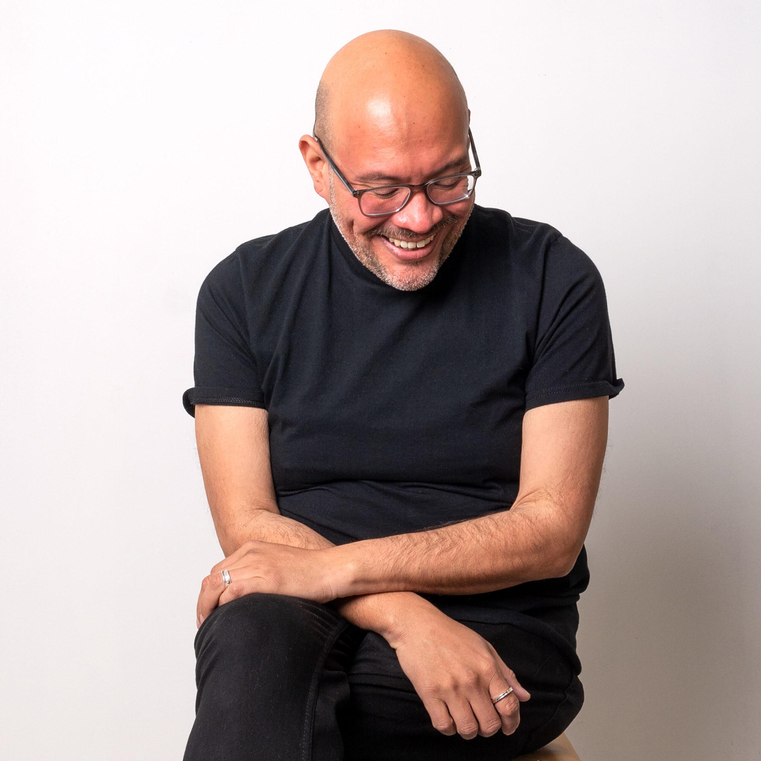 Jose Santiago Perez sitting with arms crossed and smiling