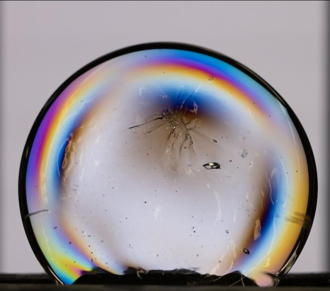 Cracked glass sphere with arc of rainbow light around the edge