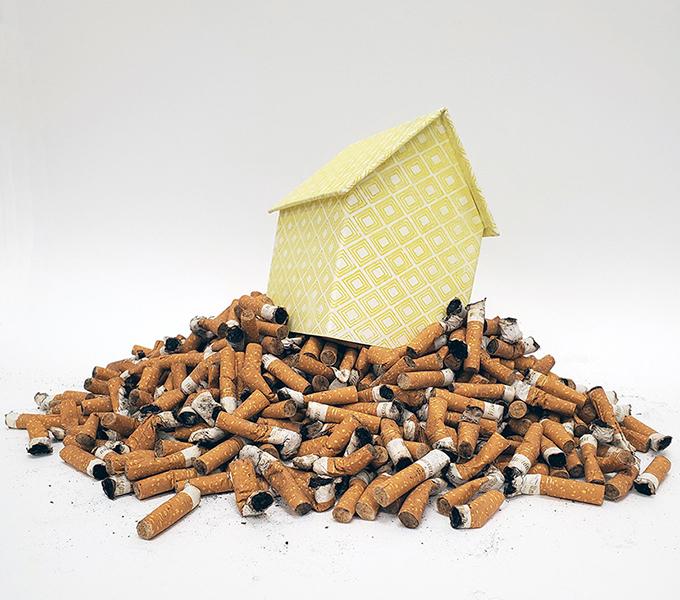 Paper house with yellow pattern on a pile of cigarette butts