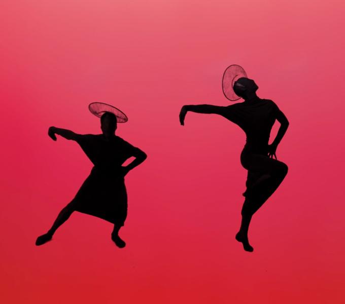 Two figures in black silhouette dance on pink background